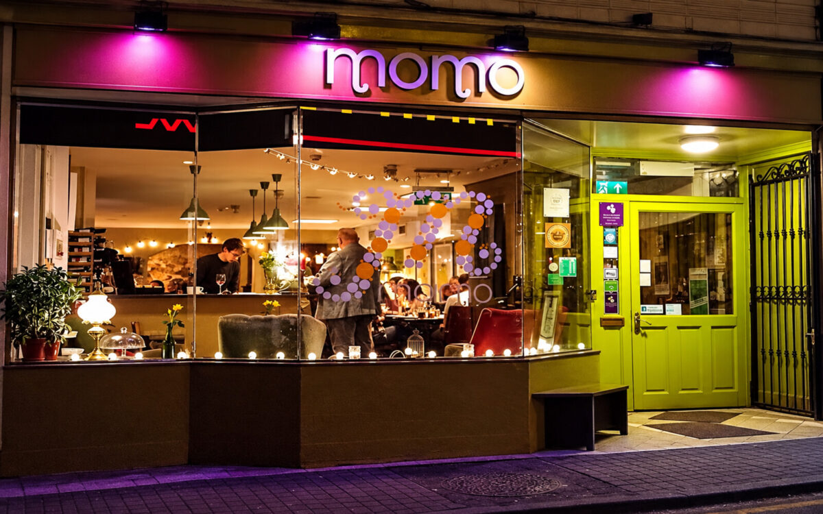 Front entrance and illuminated Momo sign on Patrick Street in Waterford city